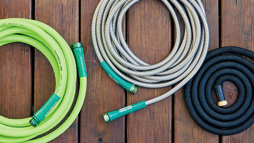 Heavy duty gardening hose with a hand sprayer attached coiled up on a metal  reel that